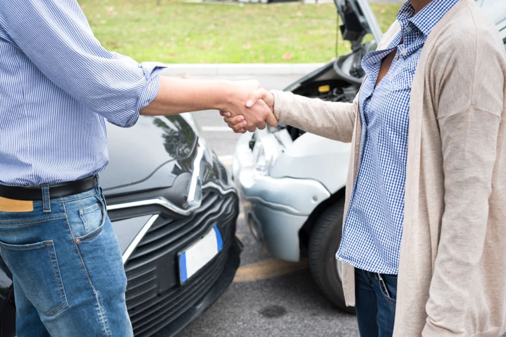 Injured parties shaking hands after reaching an agreement following a car accident