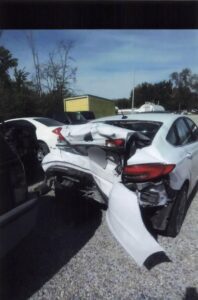 rear end view of extensive damage to the back of white sedan after car crash