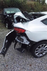 side view of extensive rear end damage on white sedan