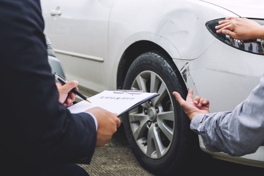 Insurance agent inspecting a car after a crash