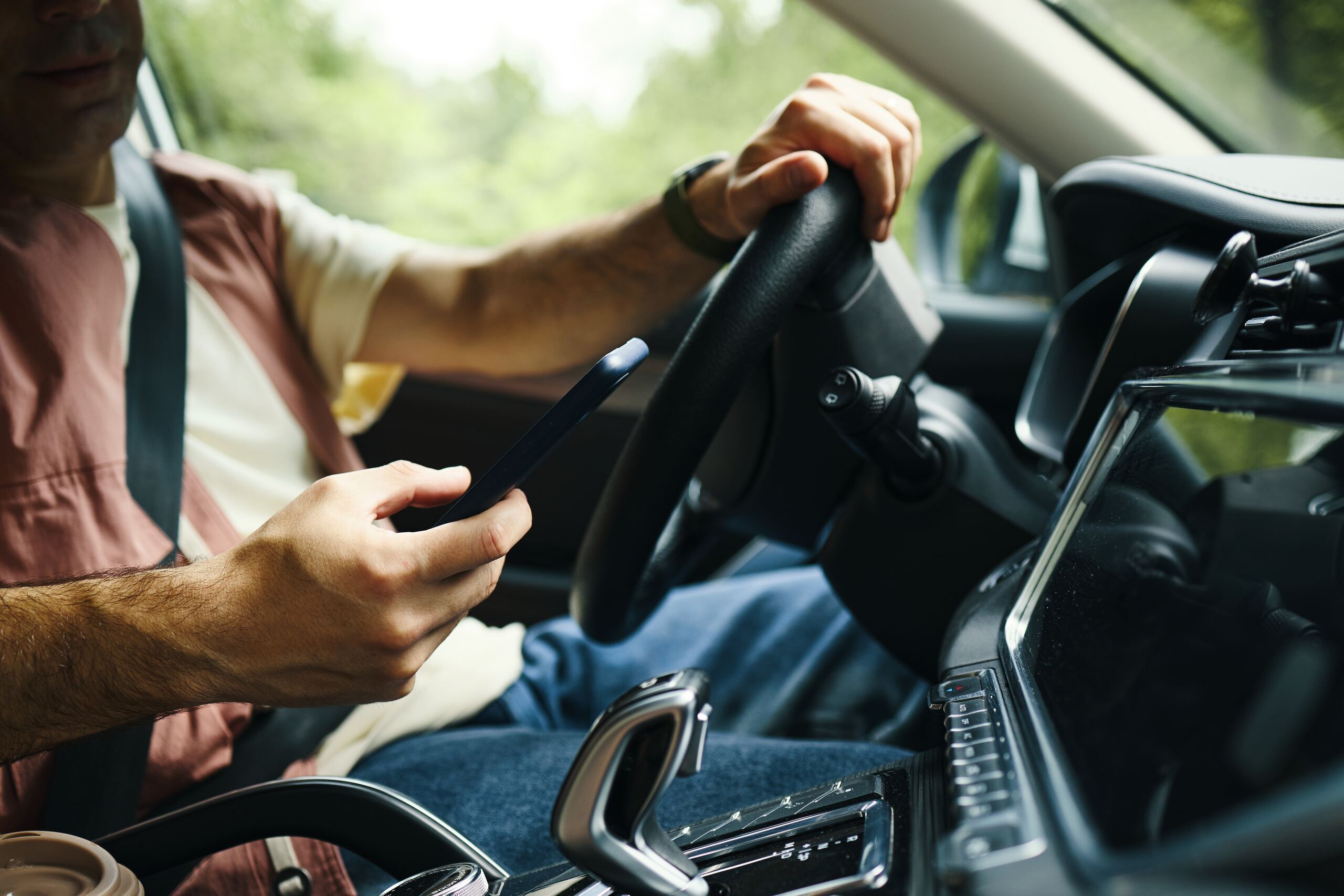 Driver using smartphone behind wheel, targeted by St. Louis Distracted Driving Accident Lawyers.