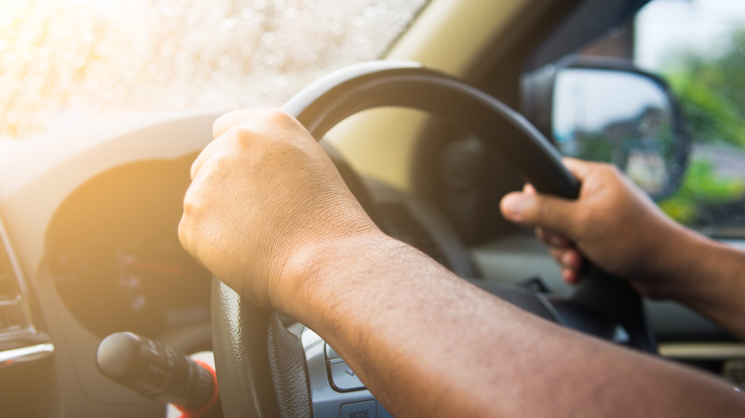 Close-up of hands on a steering wheel, representing the risk of being hit by a delivery driver in Missouri.