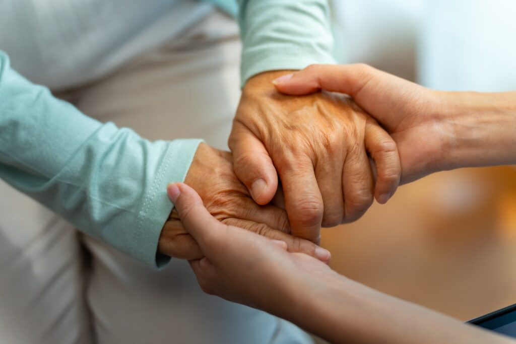 A caregiver holding an elderly person hands to provide comfort and support for St Louis nursing home abuse lawyers.